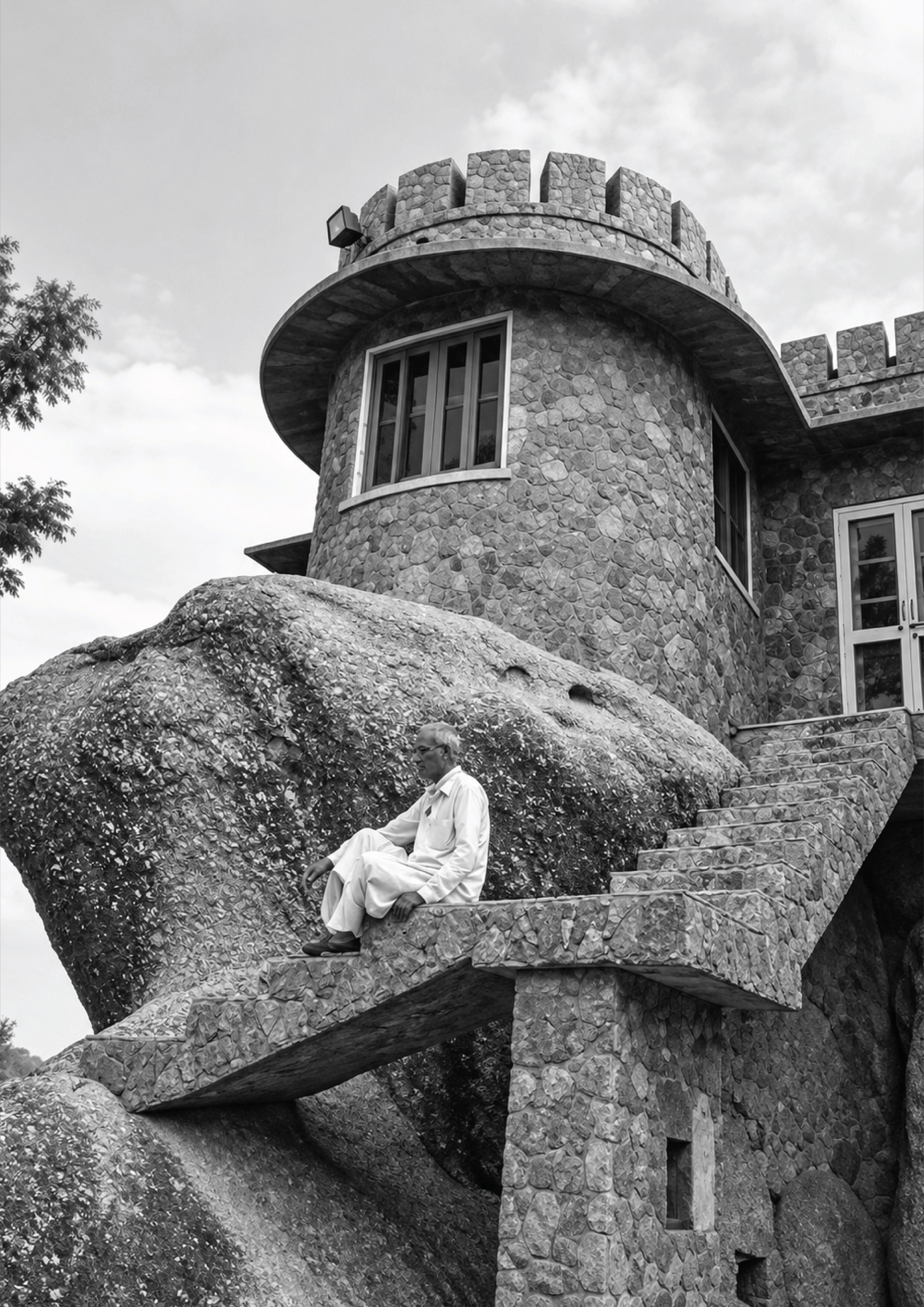 Late Shri Raj Mistri Champalal Suthar seated beside his stone-built home